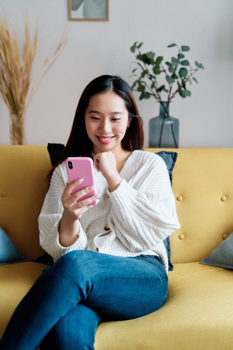 Cheerful Asian woman taking selfie on smartphone